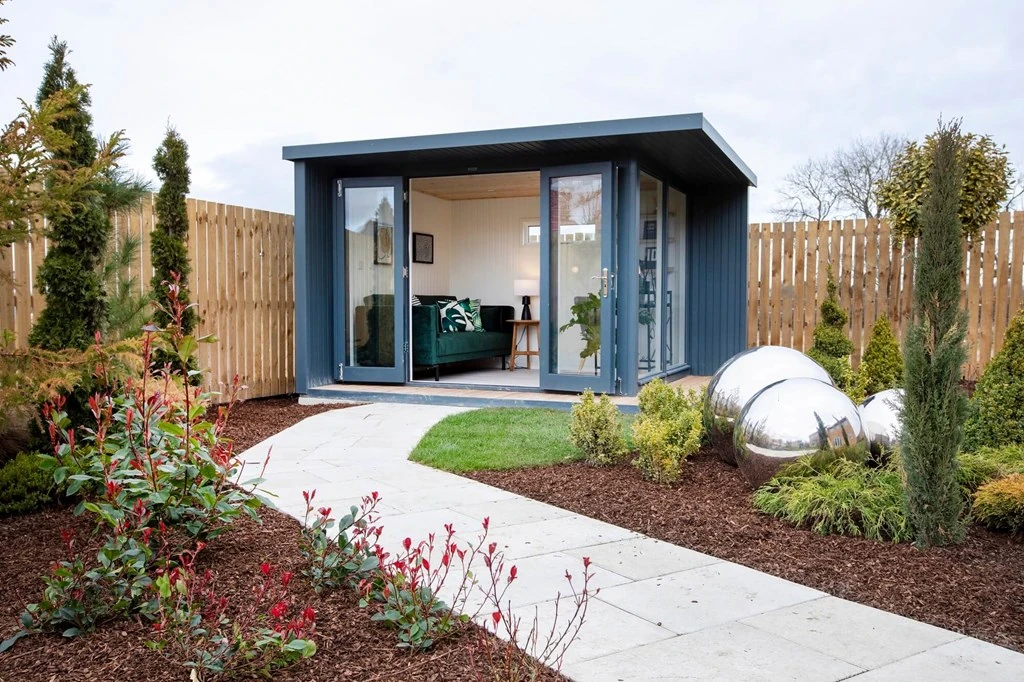 A small building in a garden containing a lounge