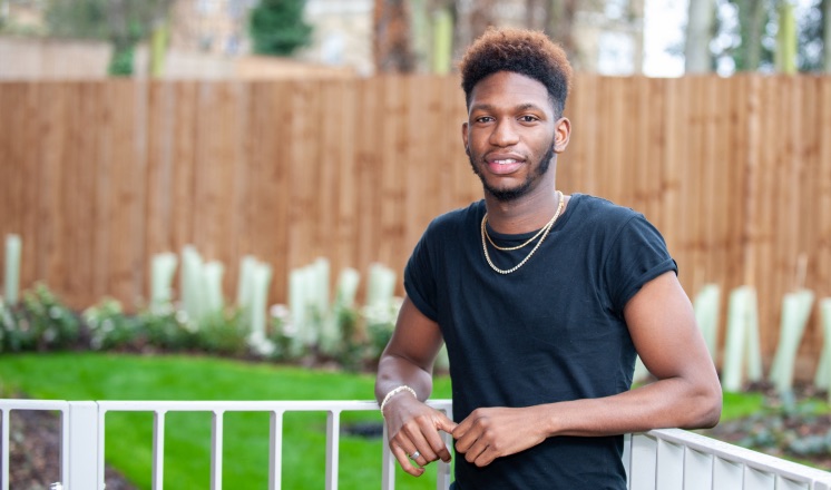 Man stood against fence